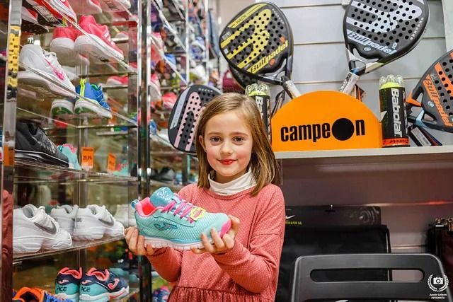 Una niña sostiene un par de zapatos en una tienda.