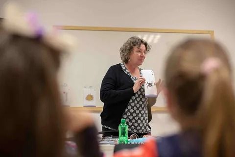 Una mujer está dando una presentación a un grupo de niños en un aula.