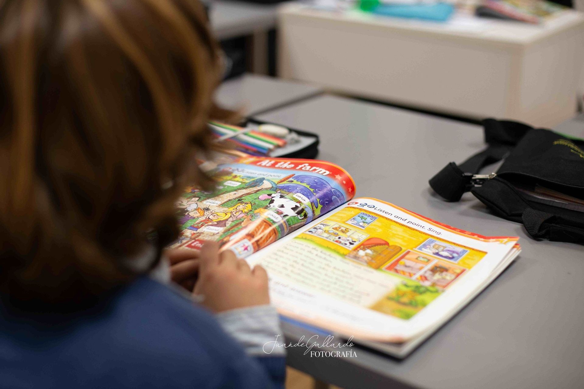 Un niño pequeño está leyendo un libro en un aula.