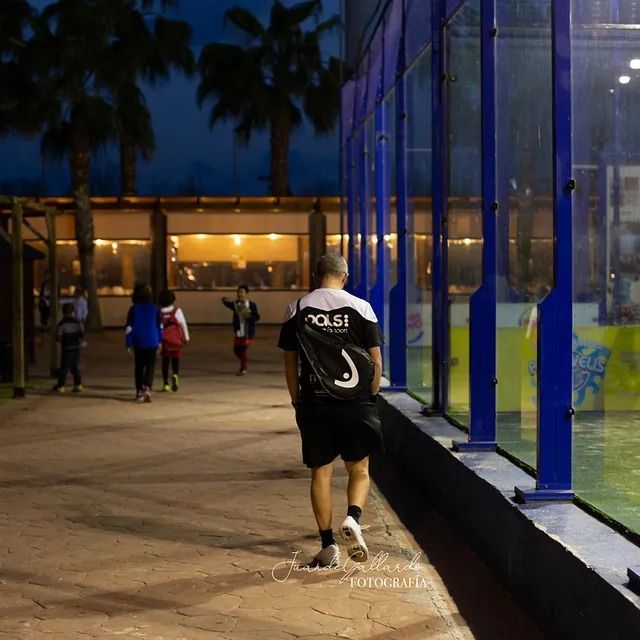 Un hombre que lleva una camiseta que dice Rossi camina por una acera de noche.