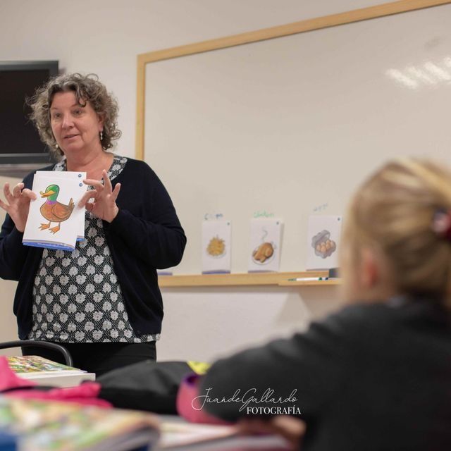 Una mujer está parada frente a una pizarra blanca sosteniendo una imagen de un pato.