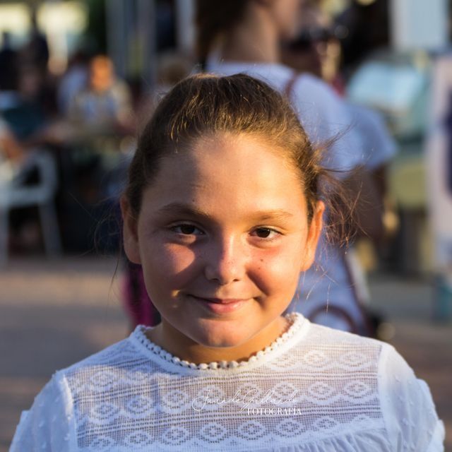 Una joven vestida con una camisa blanca y perlas sonríe a la cámara.