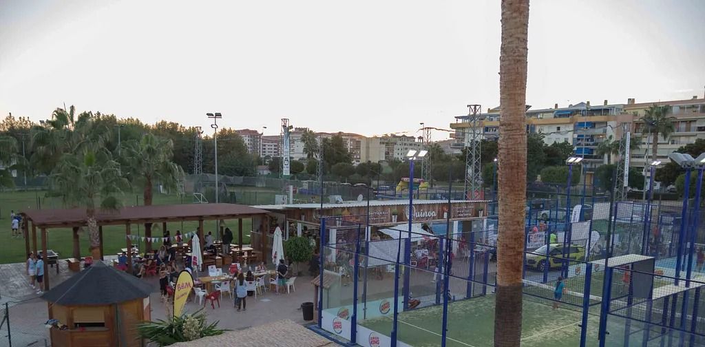 Un grupo de personas está sentada bajo una pérgola en un parque.