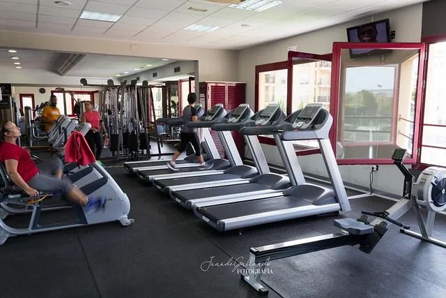 Una mujer está sentada en una cinta de correr en un gimnasio.