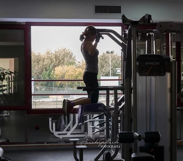 Una mujer está haciendo dominadas en un gimnasio.