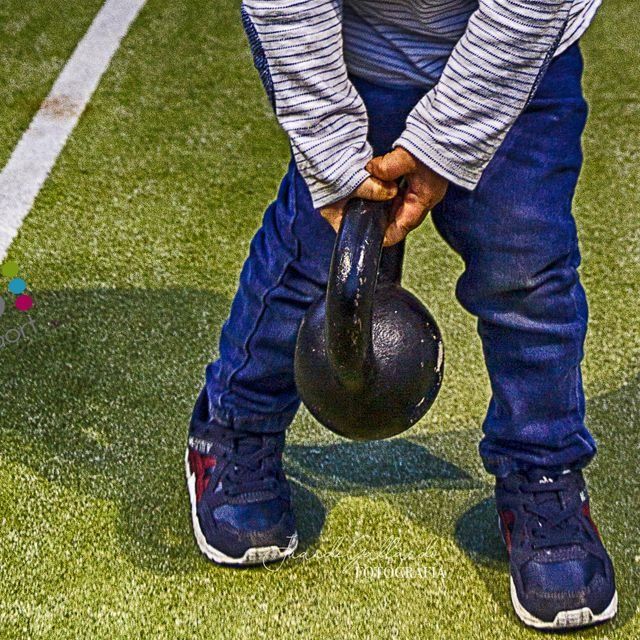 Un niño pequeño sostiene una pesa rusa en sus manos.