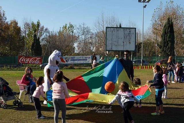 Un grupo de niños está jugando con un paracaídas colorido en un parque.