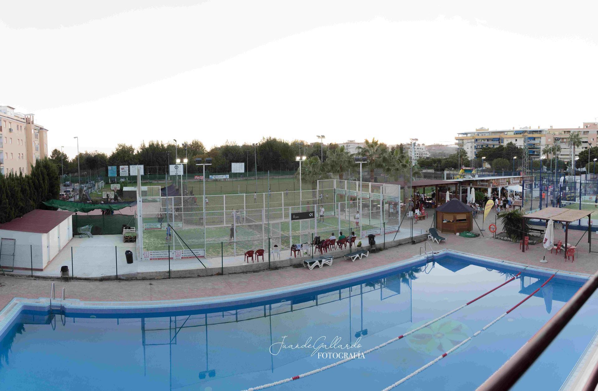 Una gran piscina con una pista de tenis al fondo.