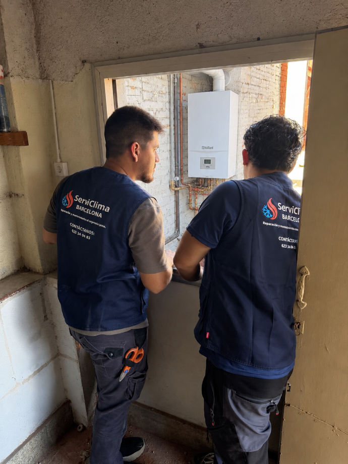 Dos técnicos con chalecos azul marino inspeccionan una puerta en el interior de un edificio en renovación.