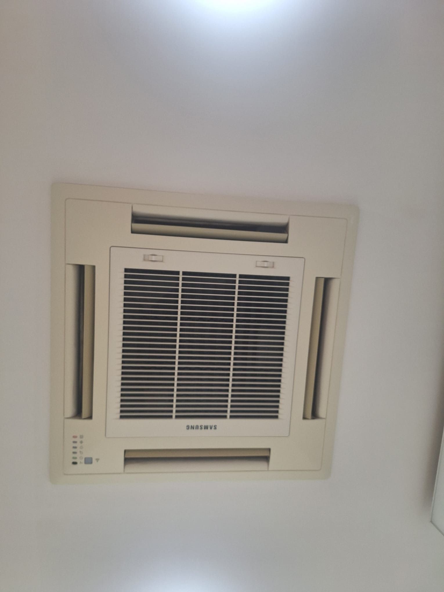 Rejilla de ventilación del aire acondicionado montada en el techo, sobre un techo blanco, centrada en el marco.