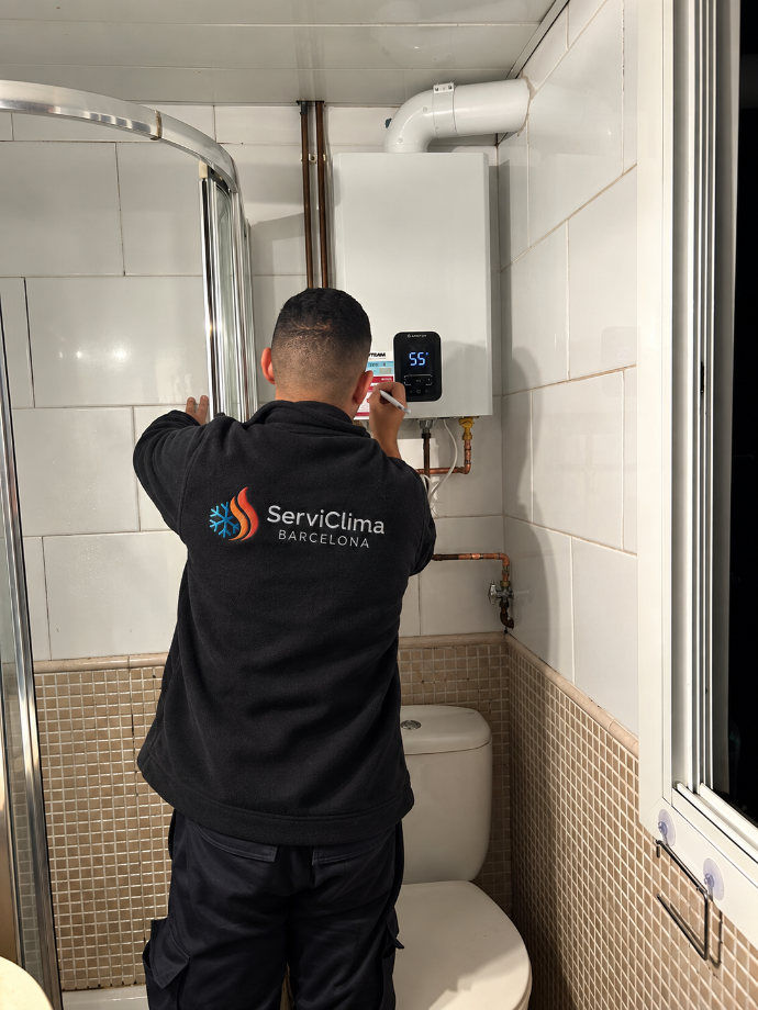 Técnico instalando un dispositivo de pared en un baño alicatado, junto al inodoro y la ducha.