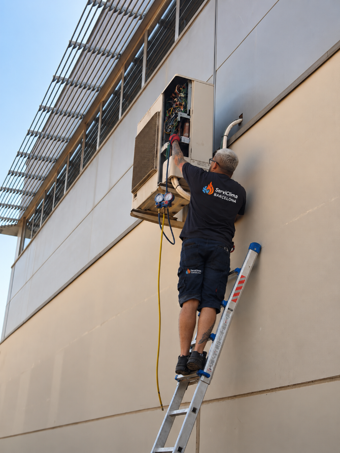 Un trabajador, subido a una escalera, repara un panel eléctrico en el lateral de un edificio.