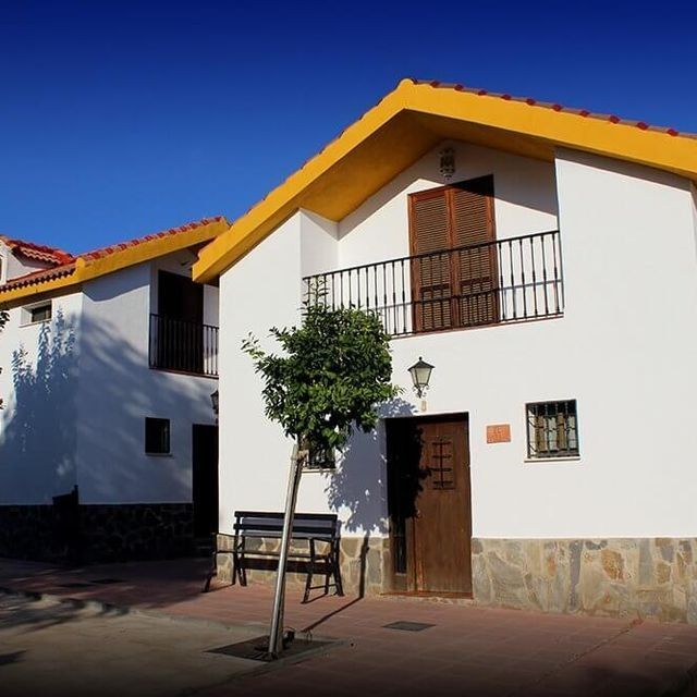 Una casa blanca con techo amarillo y un banco delante de ella.