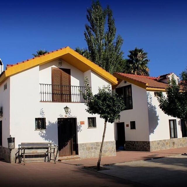 Una casa blanca con techo amarillo tiene un banco delante.