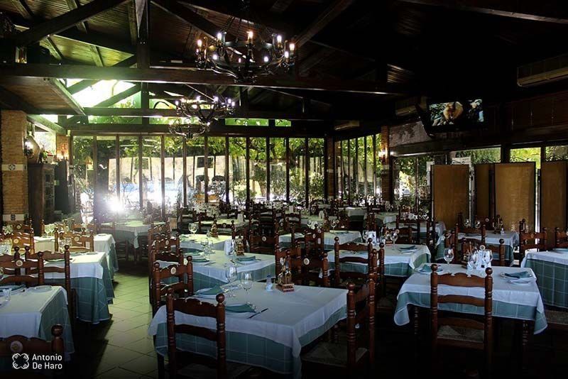 Un restaurante lleno de mesas y sillas y una lámpara de araña.