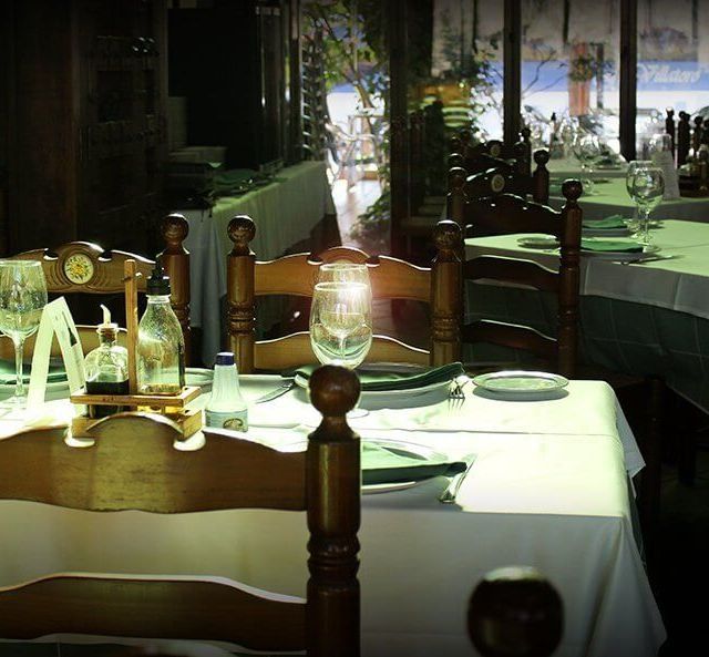 Un restaurante con mesas y sillas con platos y vasos.