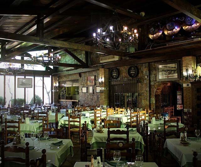 Un restaurante lleno de mesas y sillas y una lámpara de araña.