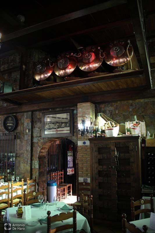 Un restaurante con mesas y sillas y barriles en el techo.