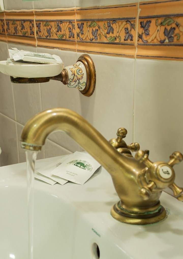 Un lavabo de baño con grifo de latón y jabonera.