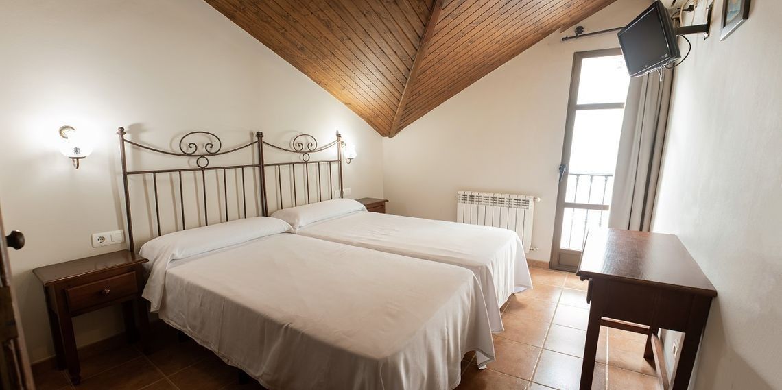 Una habitación de hotel con dos camas, una mesa y un televisor.