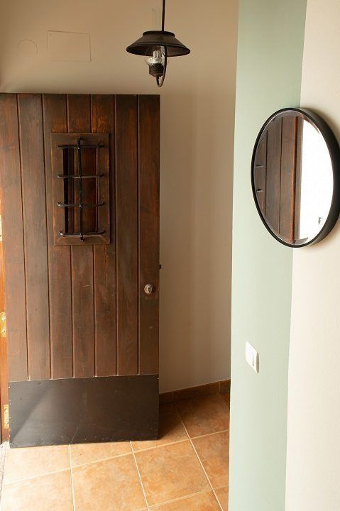 Un pasillo con una puerta de madera y un espejo.