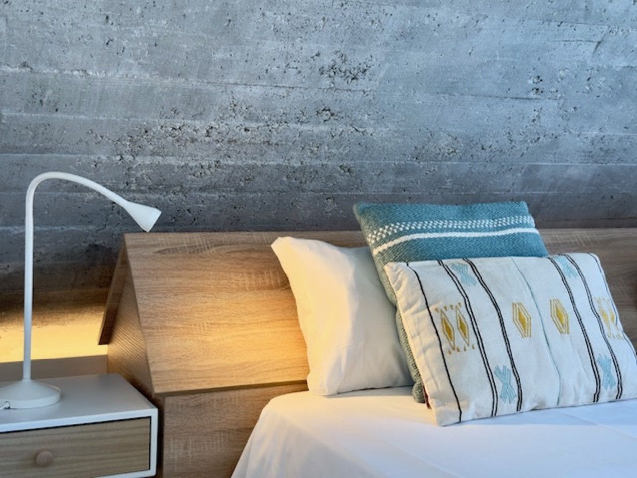 Un dormitorio con cama, mesita de noche y lámpara.