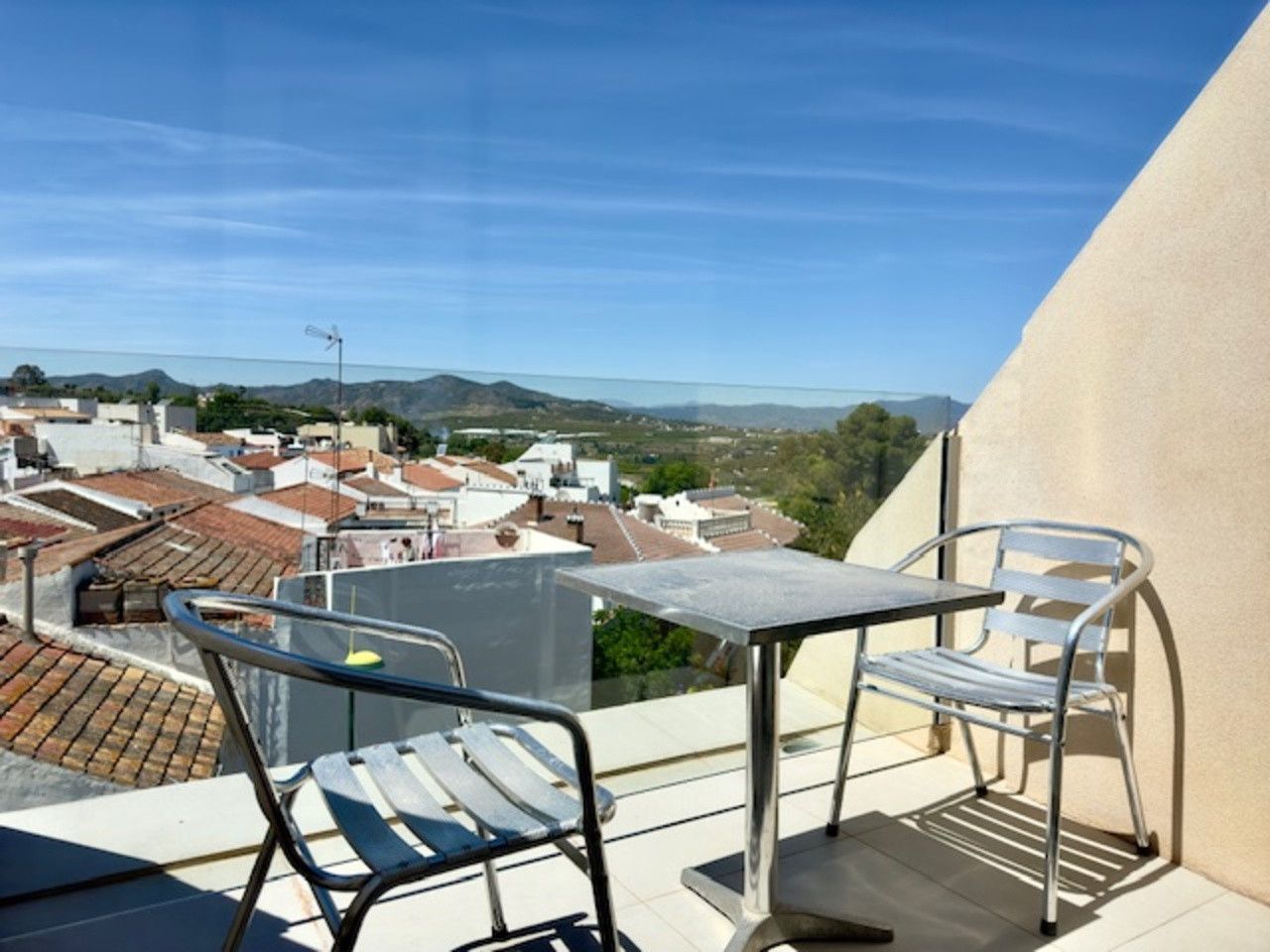 Dos sillas y una mesa en un balcón con vistas a una ciudad.