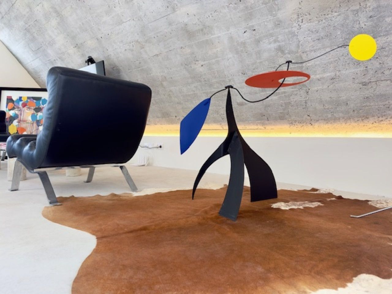 Una escultura está sentada sobre una alfombra de piel de vaca en una sala de estar.