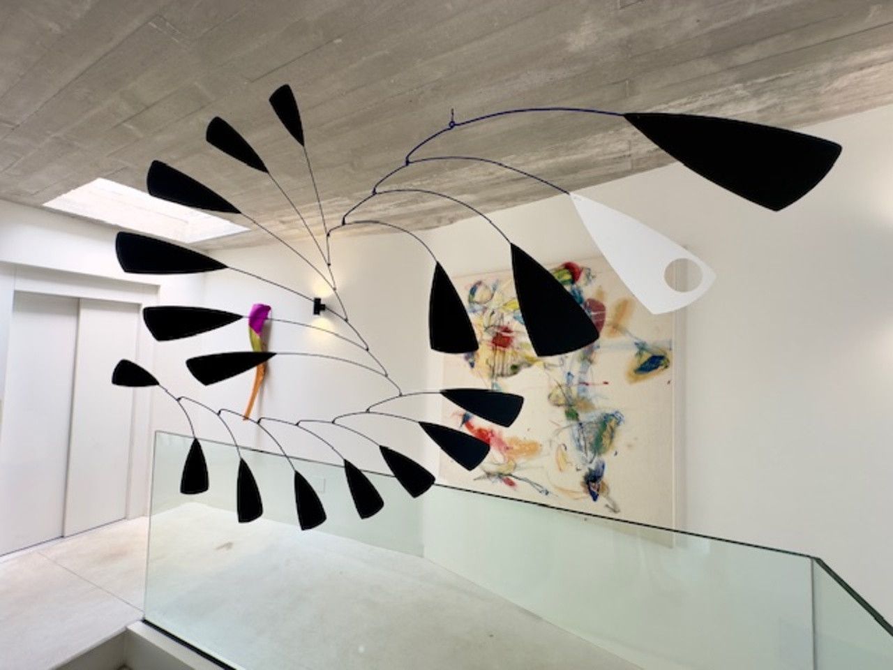 Una escultura móvil cuelga del techo en un pasillo.