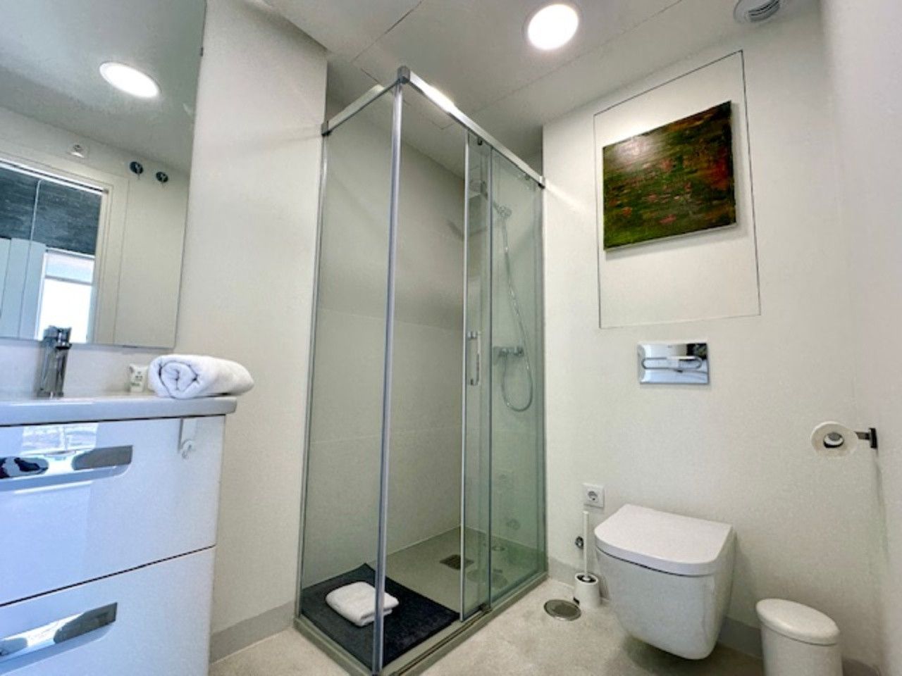 Un baño con inodoro, lavabo, ducha y espejo.