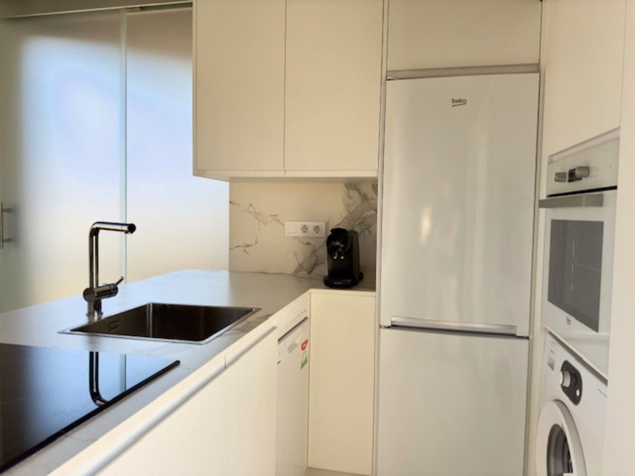 Una cocina con fregadero, frigorífico y microondas.