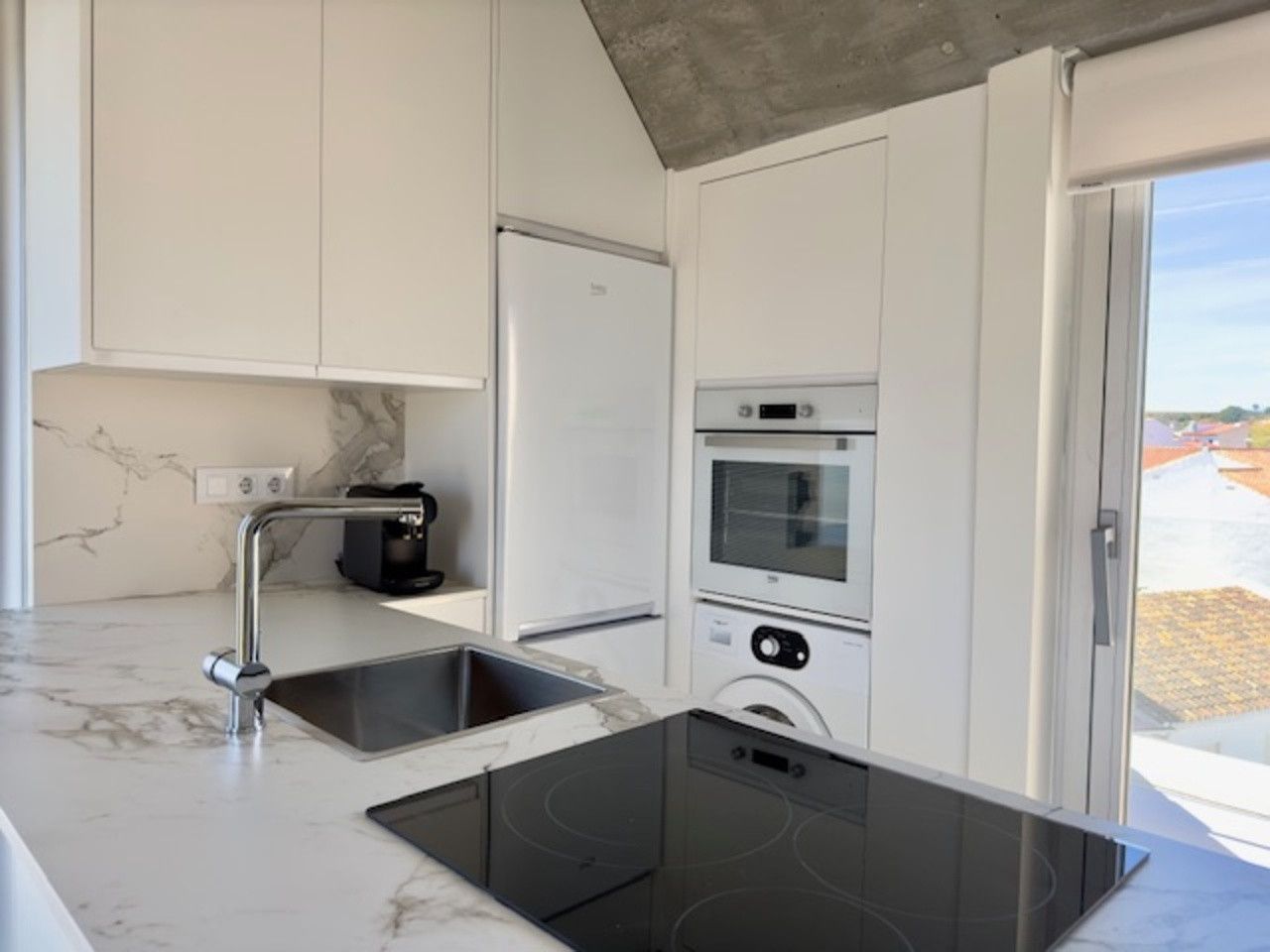 Una cocina con fregadero, horno, lavadora y secadora.