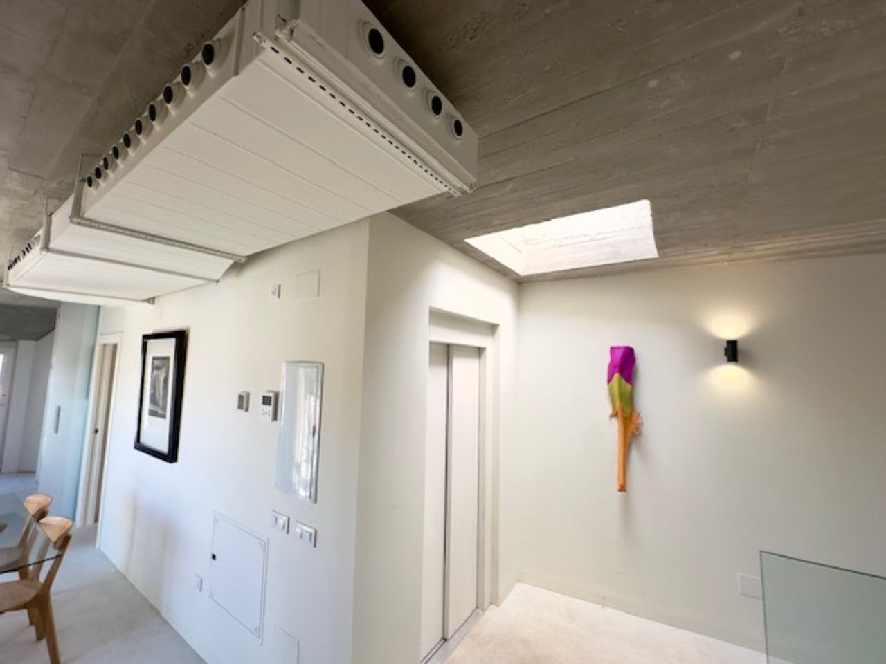 Un pasillo con ascensor y un cuadro en la pared.