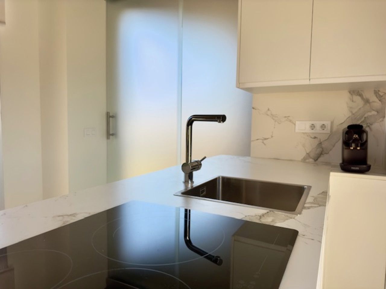 Una cocina con estufa, horno, fregadero y grifo.