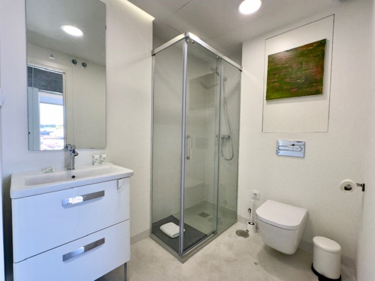 Un baño con inodoro, lavabo, ducha y espejo.