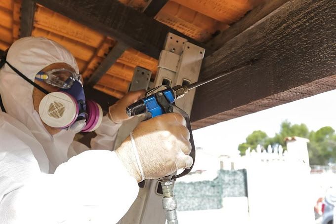 Homme avec un masque traitant du bois de charpente