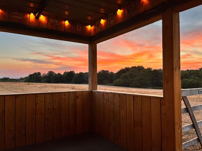 Image showing the view from a peaceful outside seating area  at Hillside Farm Apartments overlooking the fields during a beautiful sunset