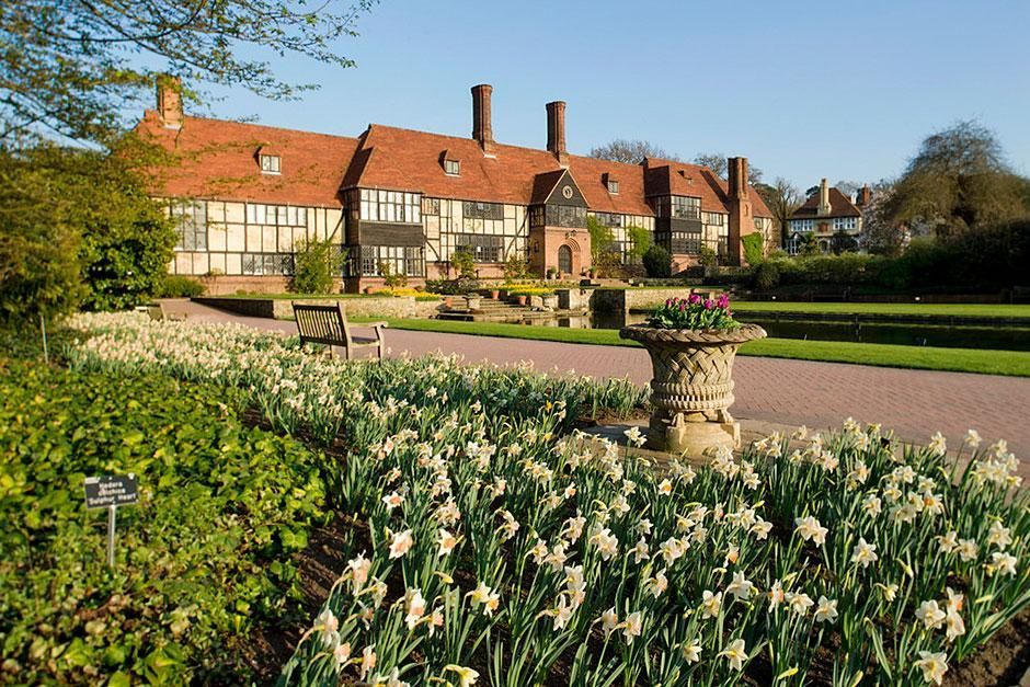 Image shows the main building at RHS Wisley Gardens in front of the formal pond