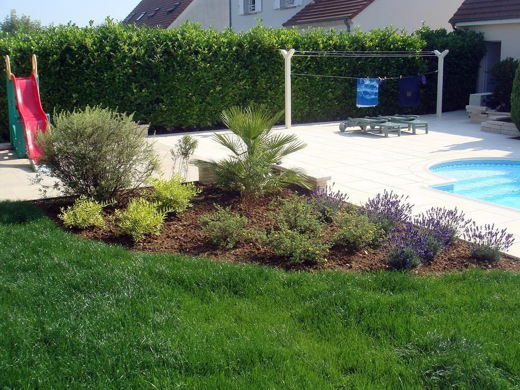 Jardin arrière luxuriant avec un parterre de fleurs, une piscine et un toboggan.