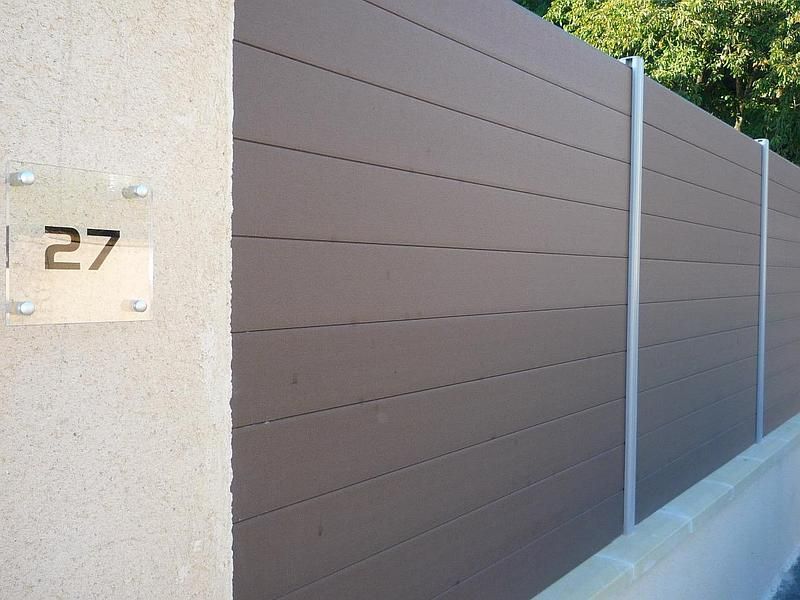 Clôture à lattes horizontales marron avec poteaux argentés et un poteau en béton portant le numéro de maison 27.