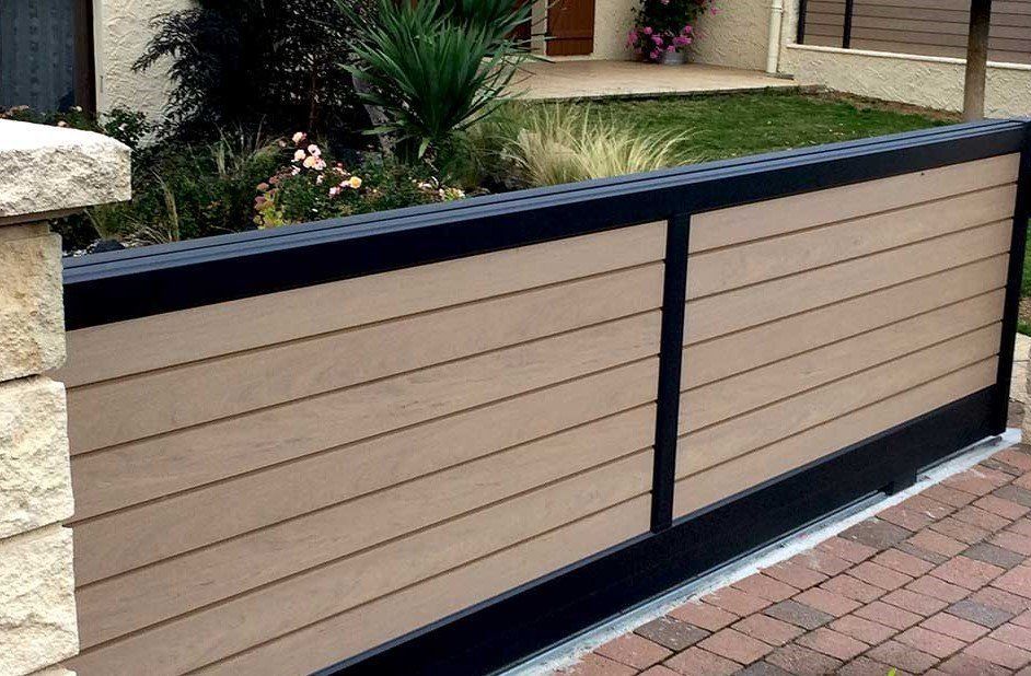 Portail coulissant à lames horizontales beiges, cadre noir, allée en briques et poteau en pierre.