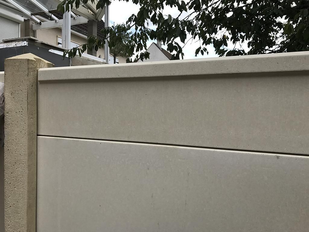 Clôture en béton beige avec une ligne horizontale, installée à l'extérieur.