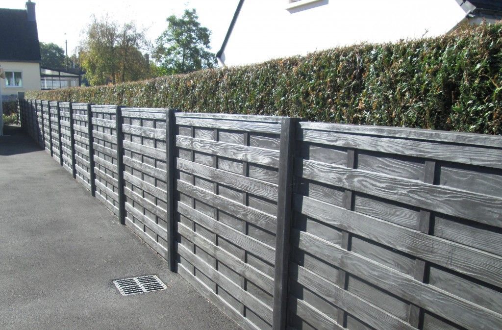 Clôture tissée gris foncé avec haie, le long d'une allée.