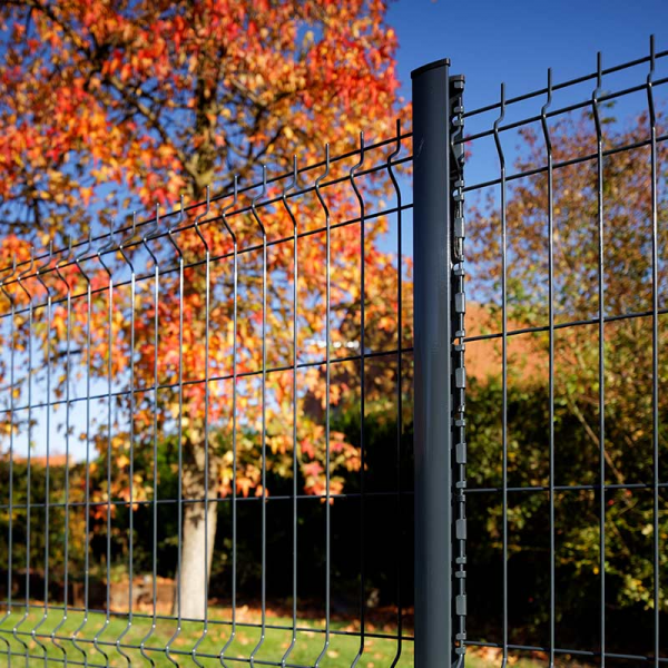 Clôture en fil de fer vert avec un poteau gris foncé, feuillage d'automne en arrière-plan.