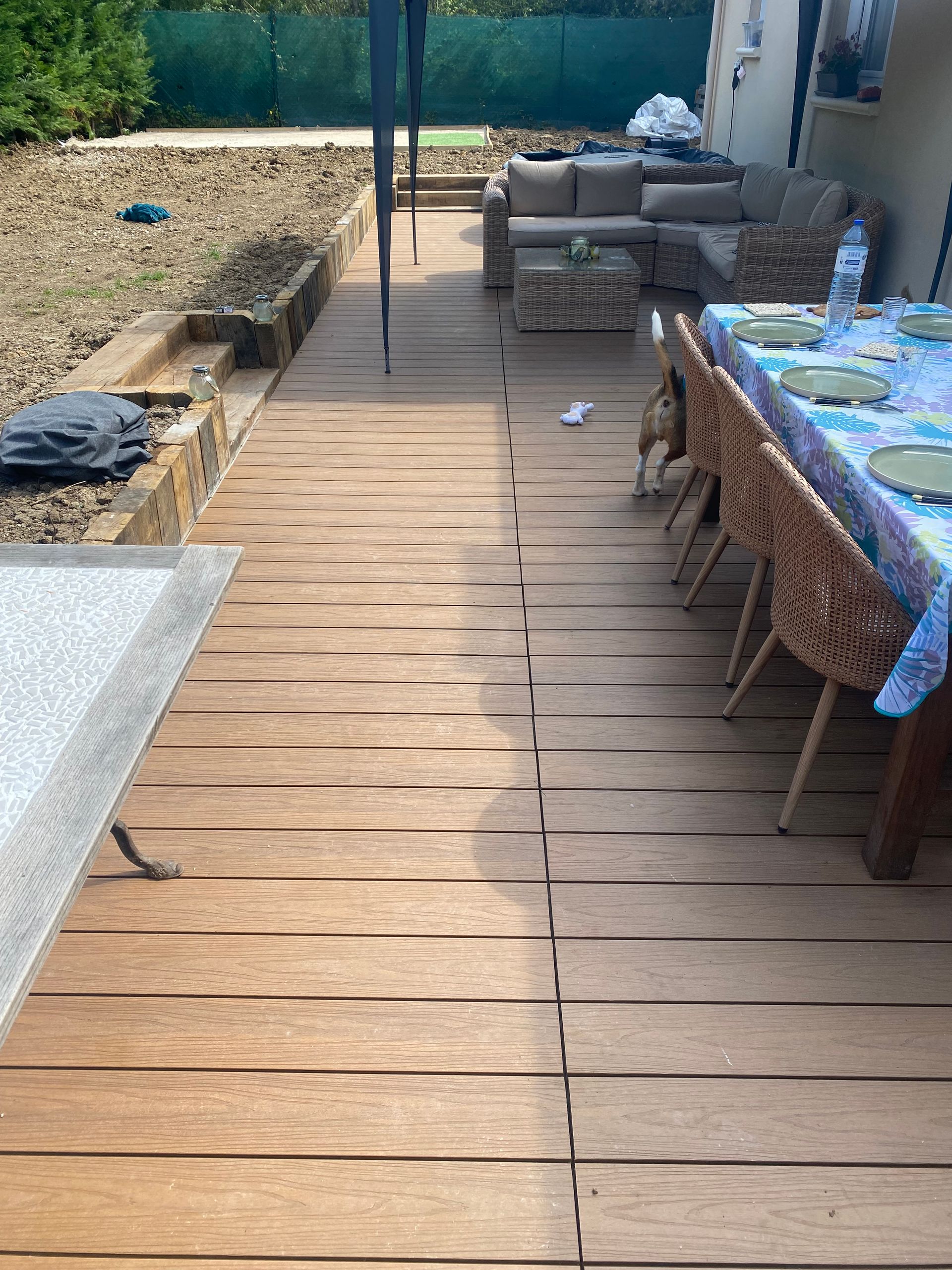 Terrasse en bois avec mobilier de jardin et table à manger dressée pour les repas.