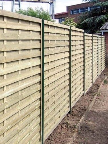 Clôture en bois avec poteaux verts verticaux, bordant une allée.