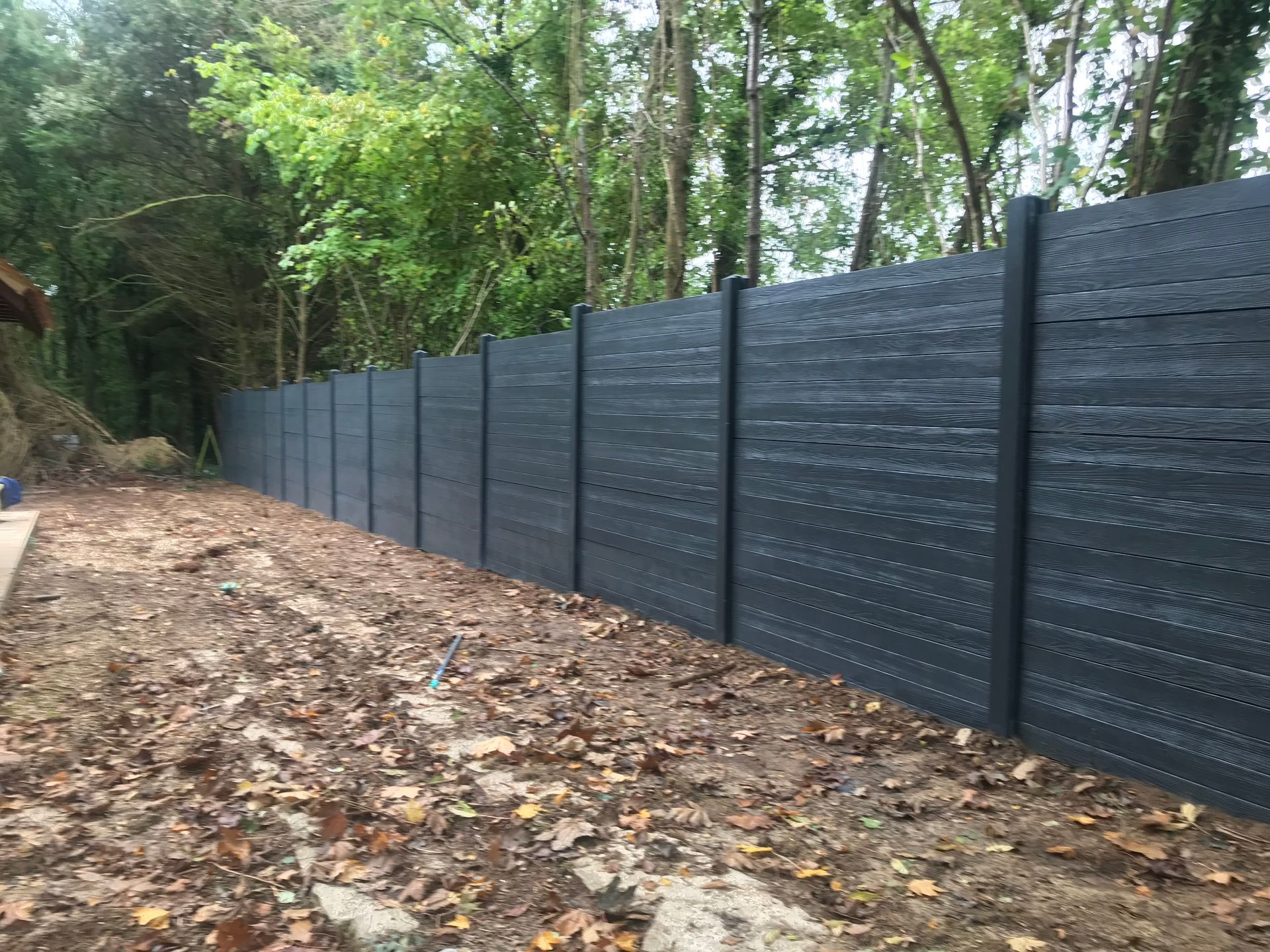 Clôture en bois gris foncé pour préserver l'intimité dans une zone boisée.