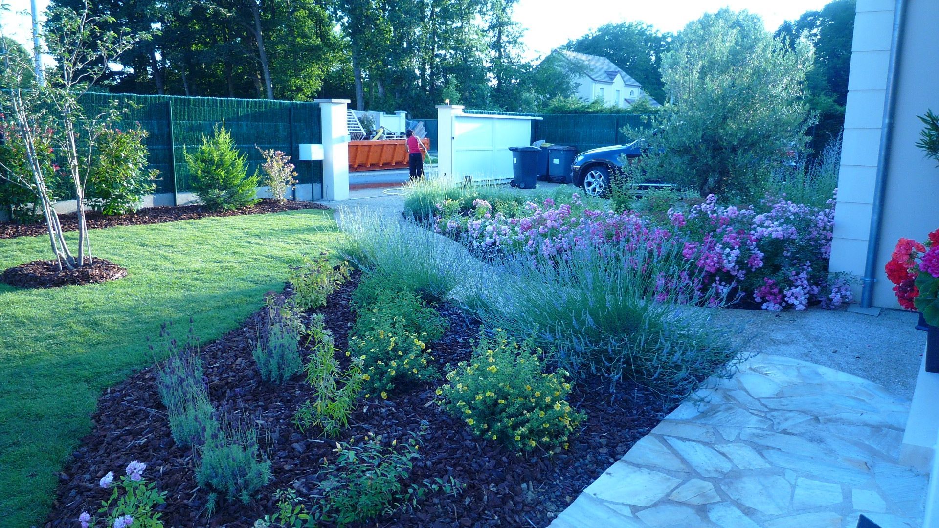 Un jardin paysager avec un chemin de pierre et des parterres de fleurs.