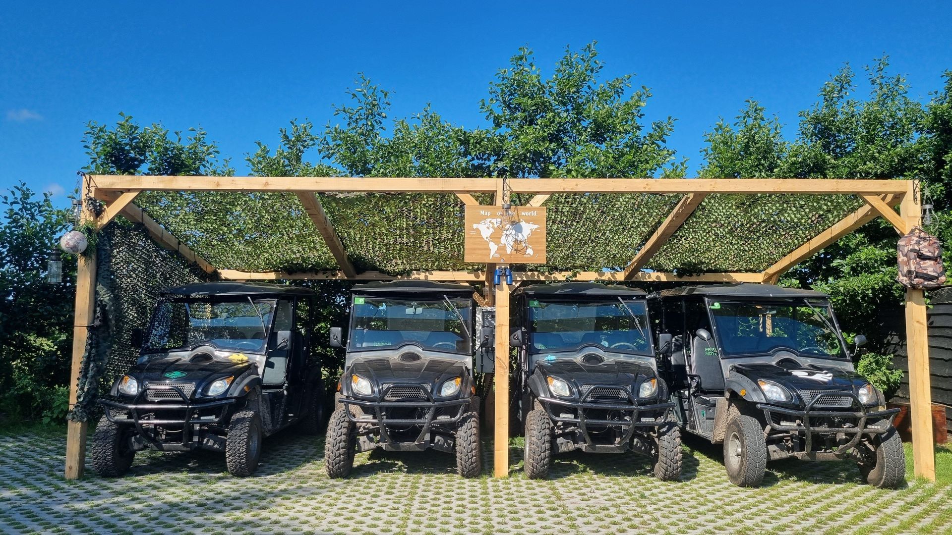 Four atvs are parked under a wooden structure.