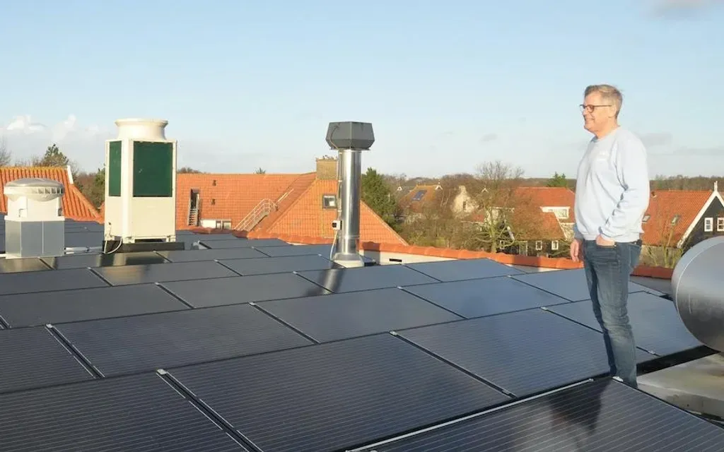 Een man die op een dak staat met zonnepanelen